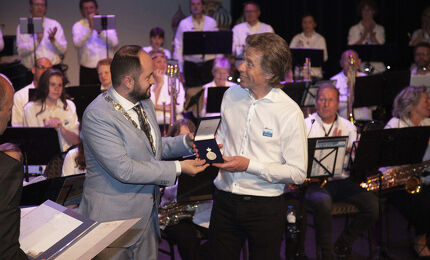 Wethouder Ufuk Kâhya biedt de onderscheiding aan 